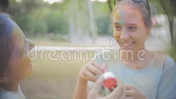 两个女孩弄脏了干燥的颜色霍利笑和吹泡泡视频的预览图
