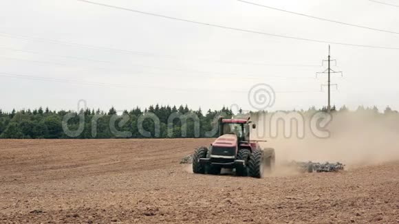 一辆农用拖拉机犁一块田移到镜头前背景中的一片森林视频的预览图