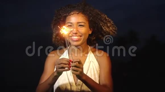 快乐的年轻女子捧着火花慢镜头地笑着庆祝一夜视频的预览图