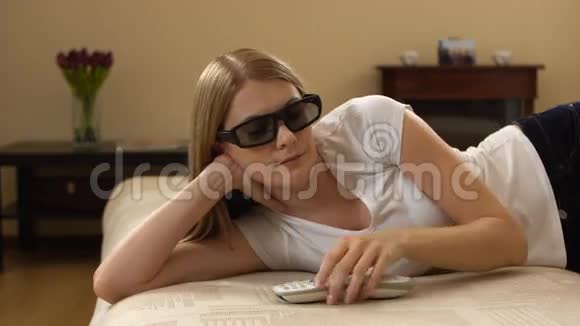 年轻漂亮的女人躺在沙发上智能电视开关3d眼镜和观看3d电影视频的预览图