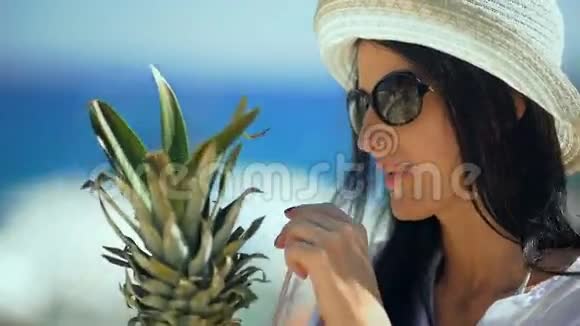 年轻漂亮的女人在海滩上喝热带鸡尾酒视频的预览图
