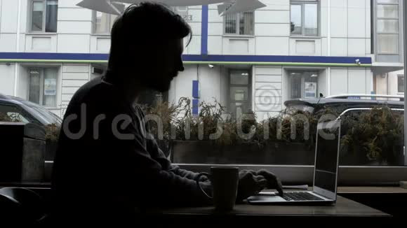 咖啡杯咖啡厅现代笔记本电脑快乐青年自由职业者剪影视频的预览图