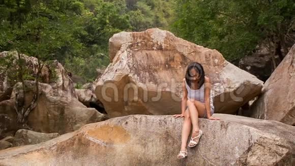 女孩从石头上下来靠在石头和山涧上视频的预览图