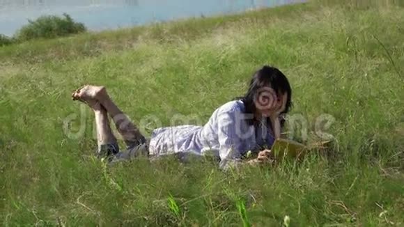 女人在湖边的绿色草坪上看书视频的预览图