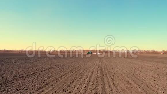 农业耕作拖拉机用大轮犁在肥沃的农田上耙土在上面扬起尘土视频的预览图