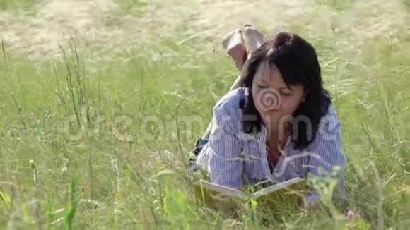 女人在湖边的绿色草坪上看书视频的预览图