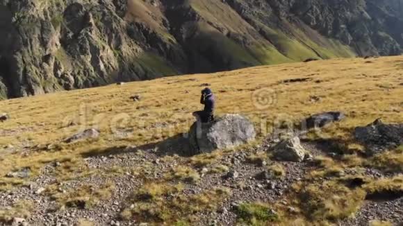 一位女摄影师在山上的高原上漫步镜头放在岩石和岩石的背景上视频的预览图
