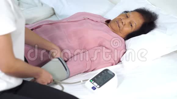 护士在床上检查一名老年妇女的血压视频的预览图