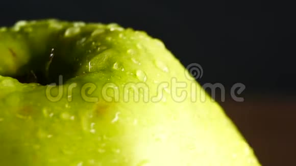 带水滴的绿苹果在黑色背景下旋转视频的预览图
