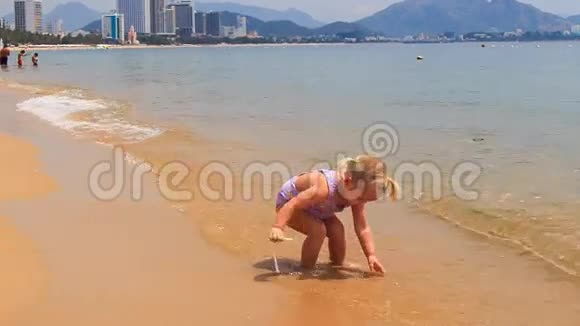 带着海尾的小女孩在沙滩上玩波浪视频的预览图