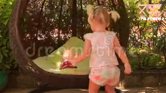一个金发小女孩带着海尾摇滚娃娃在圆圆的秋千上视频的预览图