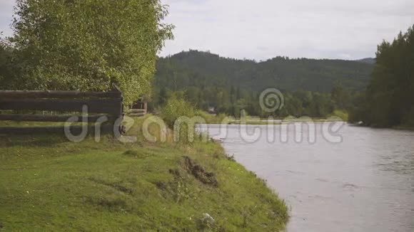 木栅栏在大河的一侧树木和山在另一侧视频的预览图