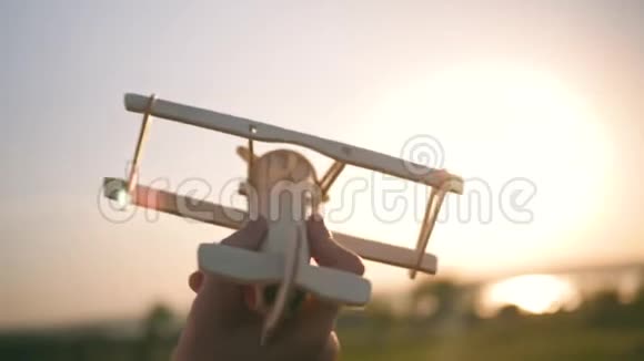 一个孩子正在日落时玩玩具飞机一个男孩拿着玩具的剪影手拿着一架小飞机这就是视频的预览图