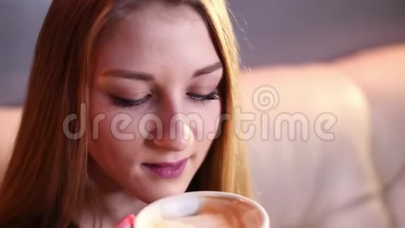金发女孩喝着咖啡在电话里聊天慢动作地坐在4k分辨率的米色沙发上视频的预览图
