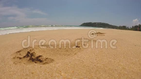 在热带海滩上的沙滩上海浪冲刷着脚印视频的预览图