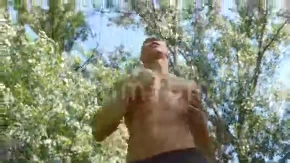 年轻的肌肉运动员在森林小径上奔跑积极的强壮的男人在户外训练身材健美的运动员视频的预览图