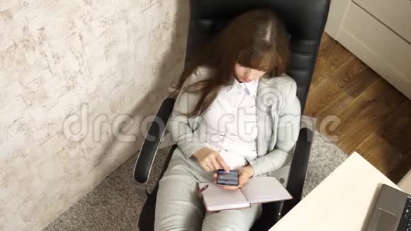 办公室里的女人在工作场所休息有电话的漂亮女商人光着脚坐在椅子上视频的预览图