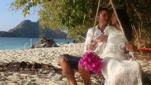 新郎和新娘在绳上翻滚在海滩上手拉手视频的预览图