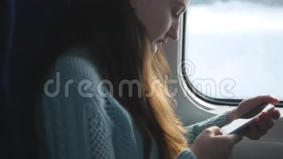 年轻女孩坐火车和使用手机漂亮的女人从智能手机上发送信息吸引力视频的预览图