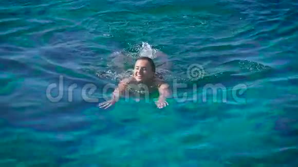 一个年轻快乐的女人在蔚蓝的大海里游泳视频的预览图