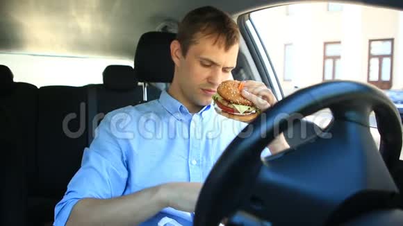 商人坐在汽车轮子旁吃快餐汉堡包视频的预览图