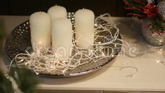 前景中装饰的圣诞树在有花环的盘子上的蜡烛上移动视频的预览图
