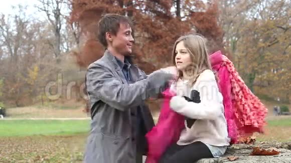 父亲在公园里帮女儿穿上夹克和围巾视频的预览图