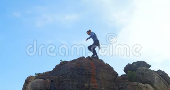 男子徒步旅行者站在岩石山顶4k视频的预览图