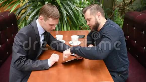 两个男人在咖啡馆用平板电脑视频的预览图