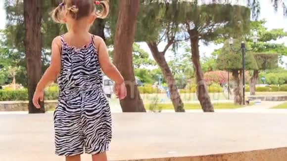 小女孩穿着斑马裙走着环形交叉的公园视频的预览图