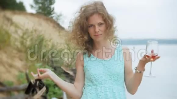 年轻的美女喝着酒杯里的酒沿着海边的沙滩散步视频的预览图