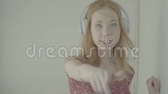 美丽的红发女人带着耳机听音乐彩色个人资料视频的预览图