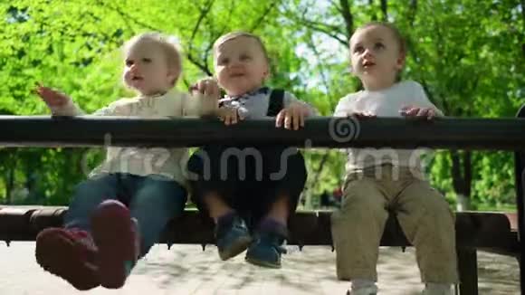 三个快乐的孩子坐在公园的长凳上视频的预览图