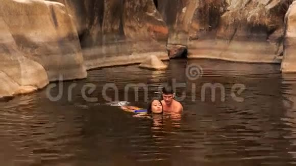 男孩帮助女孩游泳湖创造的小溪在岩石之间视频的预览图