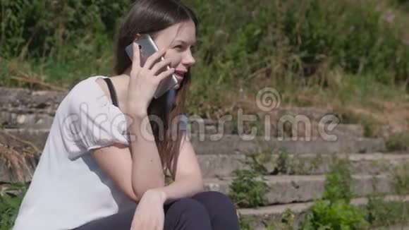 坐在公园里的年轻女人在说手机视频的预览图