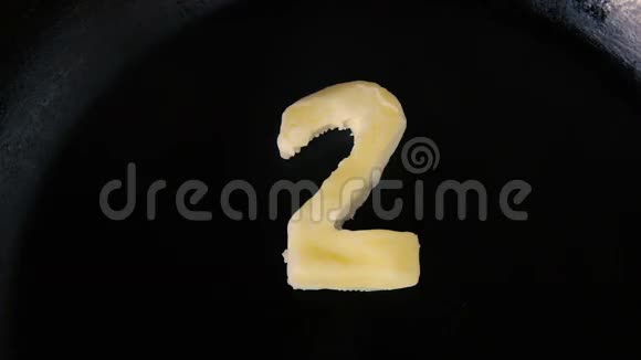 在热锅上融化2号形状的黄油关闭顶部视图视频的预览图