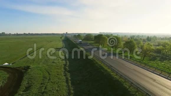 4K载有汽车在日出时行驶在绿茵场之间的道路上视频的预览图