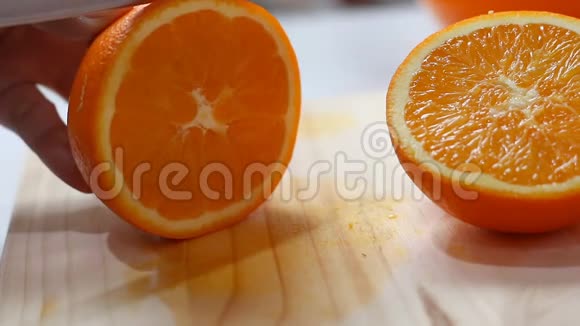 用菜刀将鲜橙和熟橙切在木刻板浅景深的地方将妇女的手收起来视频的预览图