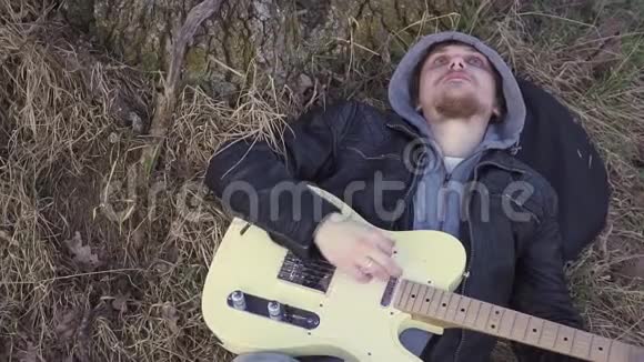 日落时分人们在靠近树的田野里弹电吉他视频的预览图