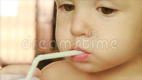 金发小女孩用吸管喝果汁的漂亮脸蛋视频的预览图