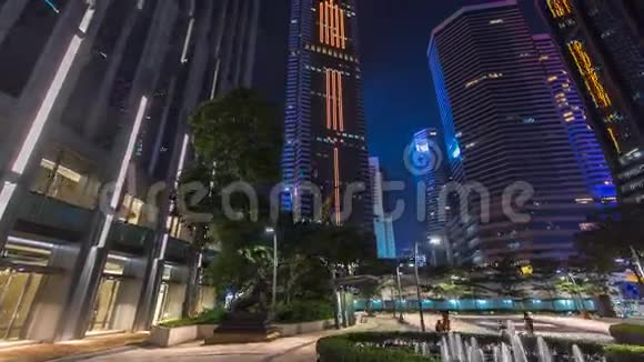 公园内有喷泉和摩天大楼环绕的现代城市夜景时光流逝香港视频的预览图