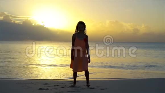 可爱的快乐小女孩在日落的白色海滩上玩得很开心视频的预览图