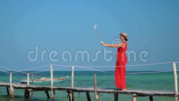 这位年轻的美女在绿松石透明水中间的一个码头上花钱岛上阳光明媚视频的预览图