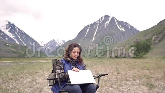 女游客带着笔记本电脑指纹作品坐在扶手椅上的群山之中视频的预览图