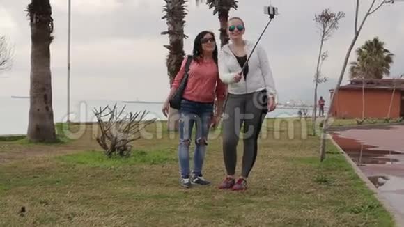 两名年轻女子使用智能手机手机相机在海滨拍摄自我肖像视频的预览图