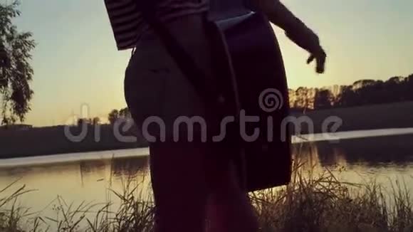 那个女孩在池塘附近的公园里弹吉他4k视频的预览图