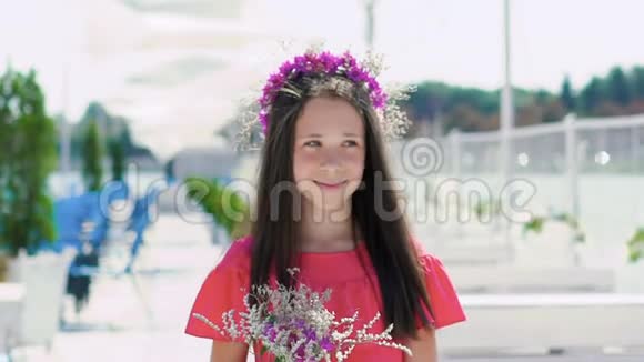 快乐的年轻女孩在手里嗅着花在海湾酒吧微笑慢慢地视频的预览图