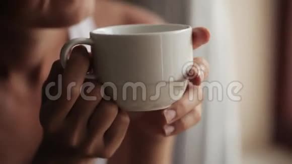 年轻漂亮的女人坐在窗边喝茶视频的预览图