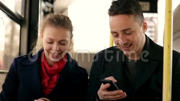 年轻夫妇坐在公共汽车上使用智能手机视频的预览图