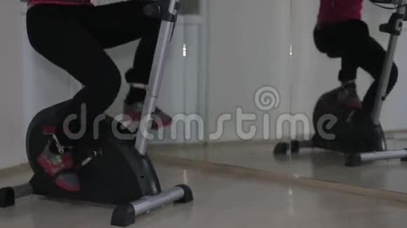 穿运动鞋的妇女在健身房的固定自行车上蹬腿视频的预览图